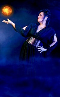 a woman in a black dress is holding a red ball in her hand